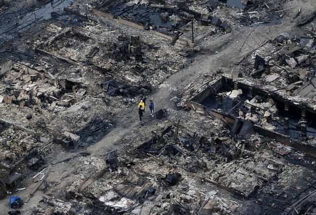 Breezy Point, a tiny beachfront neighborhood told to evacuate before Sandy hit New York, burned down as it was inundated by floodwaters, transforming a quaint corner of the Rockaways into a smoke-filled debris field. (Photo by Mike Groll/Associated Press)
