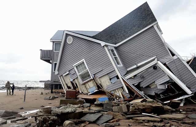 People stand next to a house that collapsed during superstorm Sandy in East Haven, Conn. (Photo by Jessica Hill/Associated Press)