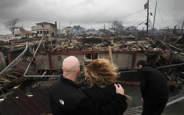 Robert Connolly, left, embraces his wife Laura as they survey the remains of the home owned by her parents in Breezy Point. (Photo by Mark Lennihan/Associated Press)
