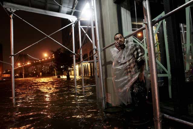 Victor Concepcion stands on a trash can above floodwaters in Brooklyn. (Photo by Kirsten Luce/The New York Times)
