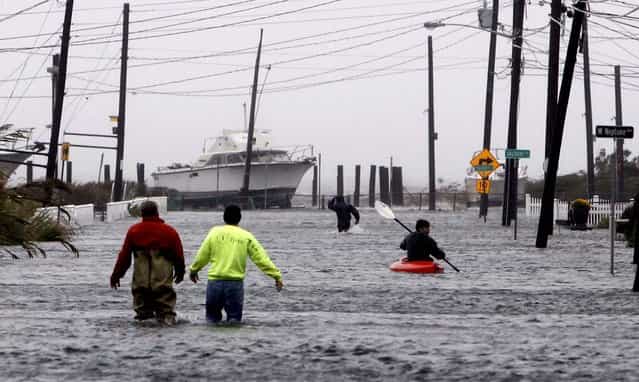 People wade and paddle down a flooded street as Hurricane Sandy approaches in Lindenhurst, N.Y. (Photo by Jason DeCrow/Asociated Press)