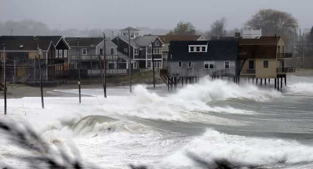 Ocean waves kick up near homes along Peggoty Beach in Scituate, Massachusetts on Monday. (Photo by Elise Amendola/Associated Press)