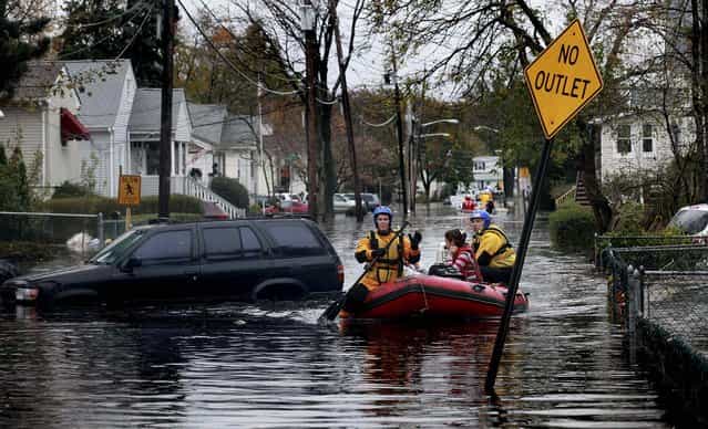 Residents are rescued from floodwaters after a levee broke in a neighboring town, in Little Ferry, N.J. (Photo by Fred R. Conrad/The New York Times)