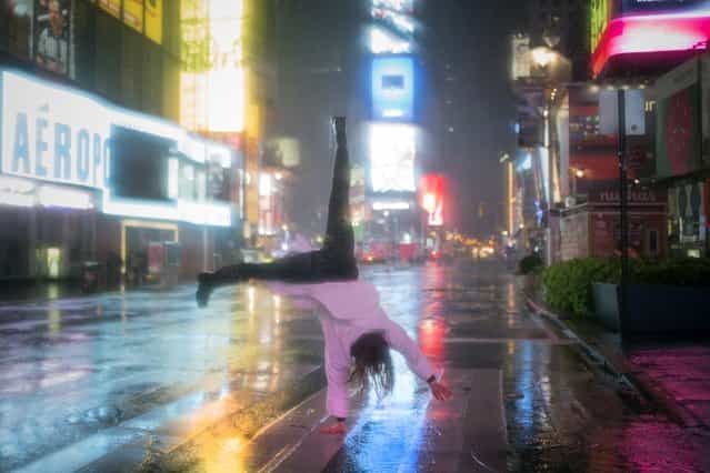 A visitor in a bathrobe does a cartwheel in the rain while visiting Times Square in New York October 29, 2012. As Hurricane Sandy aimed straight for them, promising to hammer the place they live with lashing winds and extensive flooding, New Yorkers seemed to be all about nonchalance on Monday morning – an attitude that didn't last into the afternoon. (Photo by Adrees Latif/Reuters)