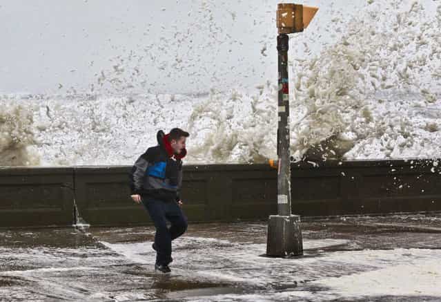 A man reacts to waves crashing over a seawall in Narragansett, Rhode Island. (Photo by Steven Senne/Associated Press)