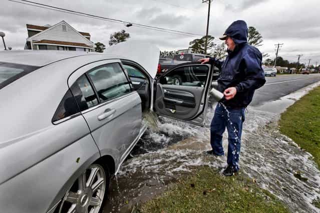 Glenn Heartley watches floodwaters from superstorm Sandy pour out of his car after it was pulled out of a creek in Chincoteague, Va., Tuesday, Oct. 30, 2012. Heartley and his wife were swept off the road into a shallow creek during Monday's storm. (Photo by Steve Helber/AP Photo)