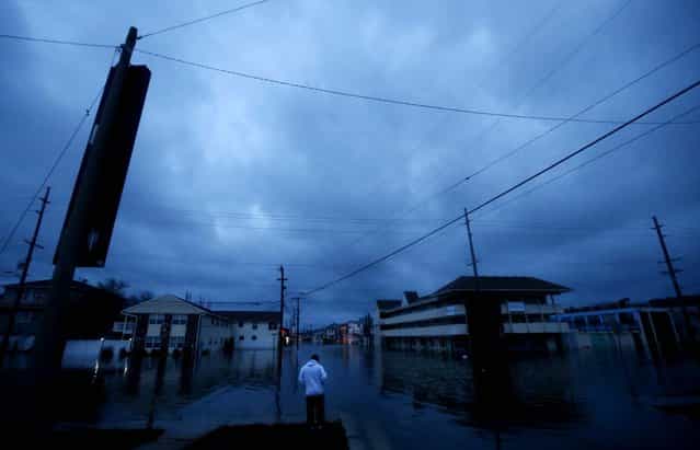 With nightfall approaching, Rodrigo Vargas, 25, of Seaside Heights, N.J., ponders treading through floodwaters to check on his second floor apartment. (Photo by Julio Cortez/Associated Press)