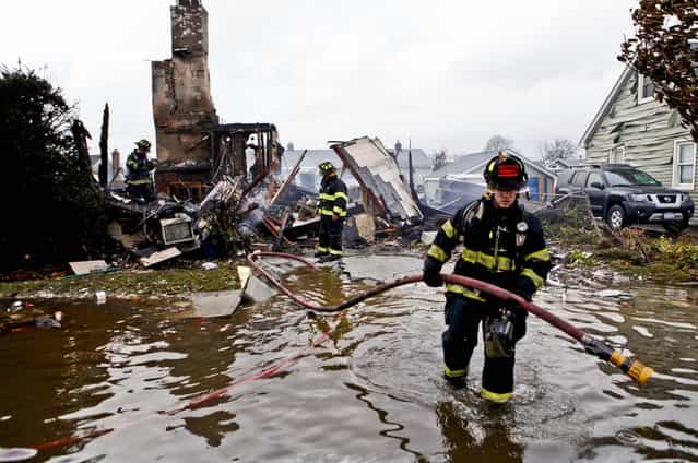 Firefighters work at the scene of a house fire in Lindenhurst, New York. According to firefighters at the scene, four homes were destroyed by fire overnight in Lindenhurst, and six in Massapequa. (Photo by Jason DeCrow/AP Photo)