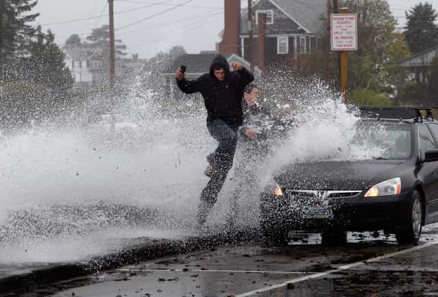 Caleb Lavoie, 17, of Dayton, Maine, front, and Curtis Huard, 16, of Arundel, Maine, leap out of the way as a large wave crashes over a seawall on the Atlantic Ocean during the early stages of Hurricane Sandy in Kennebunk, Maine, on October 29, 2012. (Photo by Robert F. Bukaty/AP Photo)