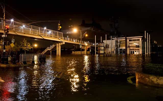 Streets along Manhattan's Westside Highway near the USS Intrepid, background center, are flooded as Sandy moves through the area. (Photo by Dylan Patrick/Associated Press)