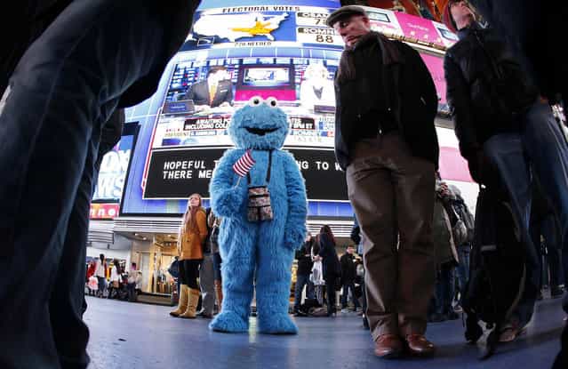 A man dressed as the character Cookie Monster watches TV screens in Times Square giving U.S presidential election results in New York November 6, 2012. (Photo by Carlo Allegri/Reuters)