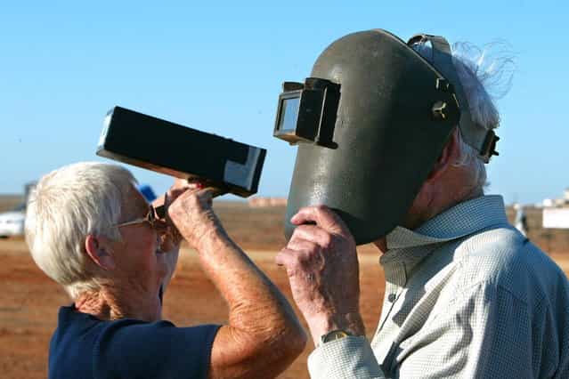 Rod (R) and Greta Handmar (L) use different techniques to observe Australia's first total solar eclipse in 26 years at Koolymilka north of the outback town of Woomera, 04 December 2002, in central Australia. Koolymilka is in a tiny 32 kilometre-wide umbral band running across the desolate state of South Australia which witnessed the eclipse shortly before sunset at 1940 local time. (Photo by Torsten Blackwood/AFP Photo)