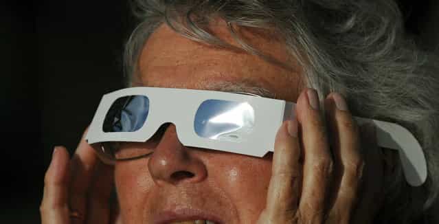 A woman wears special glasses to view the solar eclipse from the beach at Palm Cove in Australia's Tropical North Queensland on November 14, 2012. Eclipse-hunters have flocked to Queensland's tropical northeast to watch the region's first total solar eclipse in 1,300 years on November 14, which occurred as the moon passed between the earth and the sun, casting a shadow path on the globe and lasting for a maximum on the Australian mainland of 2 minutes and 5 seconds. (Photo by Greg Wood/AFP Photo)