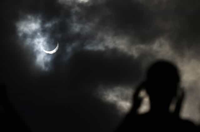 A tourist watches as the moon passing in front of the sun as it approaches a full solar eclipse in the northern Australian city of Cairns November 14, 2012. (Photo by Tim Wimborne/Reuters)