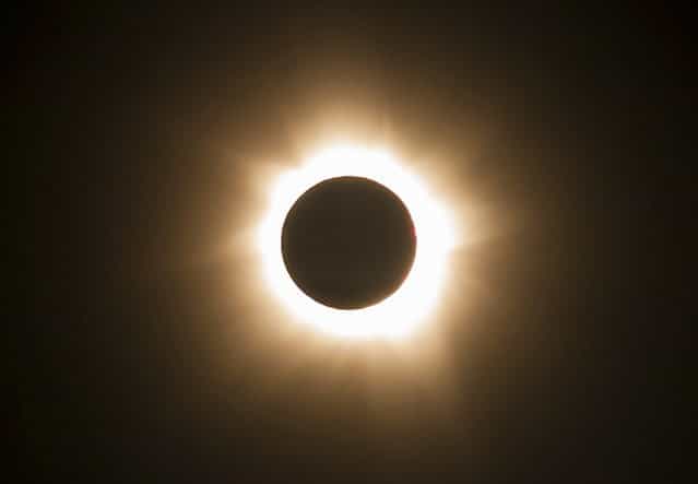 In this photo provided by Tourism Queensland, the moment of a total solar eclipse is observed at Cape Tribulation in Queensland state, Australia, Wednesday, November 14, 2012. Starting just after dawn, the eclipse cast its 150-kilometer (95-mile) shadow in Australia's Northern Territory, crossed the northeast tip of the country and was swooping east across the South Pacific, where no islands are in its direct path. (Photo by Tourism Queensland/AP Photo)