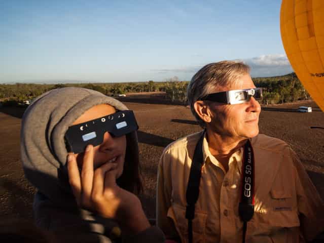 In this photo released by Hot Air Balloon Cairns, Hank Harper, right, of Los Angeles watches the solar eclipse from a hot air balloon near Cairns, Australia, Wednesday, November 14, 2012. Harper flew to Australia with his two children specially to watch the full eclipse, saying we [watched the sun's rays re-emerge from behind the moon while kangaroos hopped along the ground below]. (Photo by Hot Air Balloon Cairns/AP Photo)