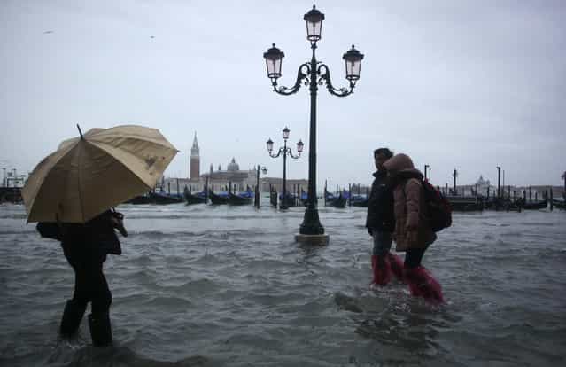 People walk through a flooded street during a period of seasonal high water in Venice November 11, 2012. The water level in the canal city rose to 149 cm (59 inches) above normal, according to local monitoring institute Center Weather Warnings and Tides. (Photo by Manuel Silvestri/Reuters)