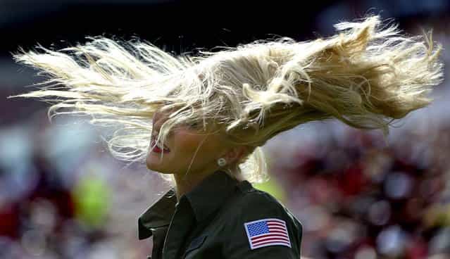 A Tampa Bay Buccaneers cheerleader, wear a military-inspired outfit as part of the NFL's Salute to Service program, flips her hair during a game between the Buccaneers and San Diego Chargers in Tampa, on November 11, 2012. (Photo by Phelan M. Ebenhack/Associated Press)