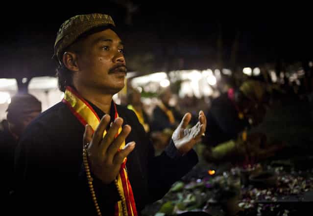 A Javanese man prays before rituals night carnival [1st Suro] ( Javanese calender) during Islamic New Year celebrations at Kasunanan Palace on November 14, 2012 in Solo City, Central Java, Indonesia. Javanese will celebrate the national holiday with ceremonies and rituals marking the 1434th Islamic New Year's Eve or [1st Suro]. The parade started from Keraton Kasunanan and is headed by a group of albino buffaloes, known as Kebo Bule. Local people believe that the parade of Heirlooms and Kebo Bule will bring them a better life. (Photo by Ulet Ifansasti)