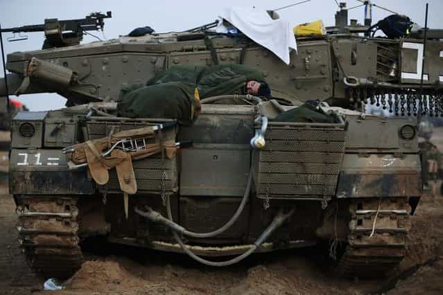 An Israeli soldier sleeps on a tank at a staging area near the Israel Gaza Strip Border, southern Israel, early Tuesday, November 20, 2012. (Photo by Lefteris Pitarakis/AP Photo)