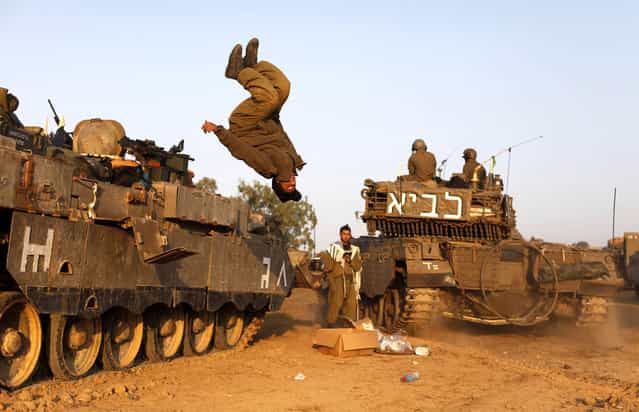 An Israeli soldier jumps from a tank in a deployment area as the conflict between Palestine and Gaza enters its seventh day on November 20, 2012 on Israel's border with the Gaza Strip. Hamas militants and Israel are continuing talks aimed at a ceasefire as the death toll in Gaza reaches over 100 with three Israelis also having been killed by rockets fired by Palestinian militants. (Photo by Lior Mizrahi)