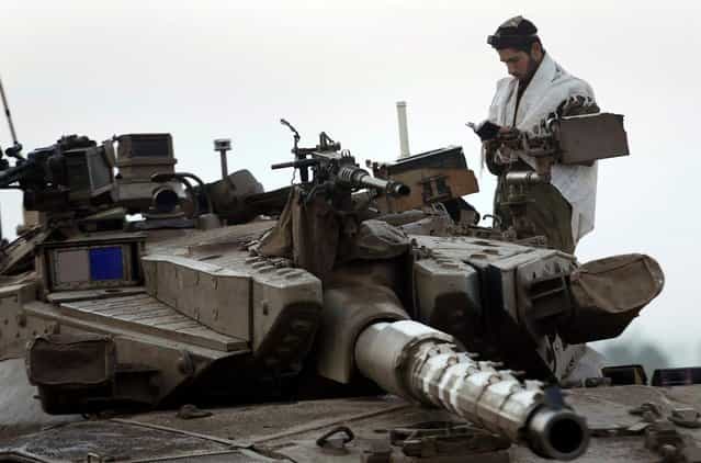 An Israeli soldier prays atop a tank at a staging area near the border with central Gaza November 20, 2012. (Photo by Yannis Behrakis/Reuters)