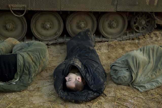 Israeli soldiers sleep next to their armored personal carriers in a staging area in southern Israel on Monday. (Photo by Ariel Schalit/Associated Press)