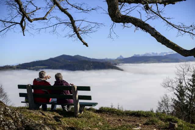 An elderly couple sit on a bench above fog hanging in the valley of Hochwacht mountain above Zug, central Switzerland on November 20, 2012. (Photo by Fabrice Coffrini/AFP Photo)