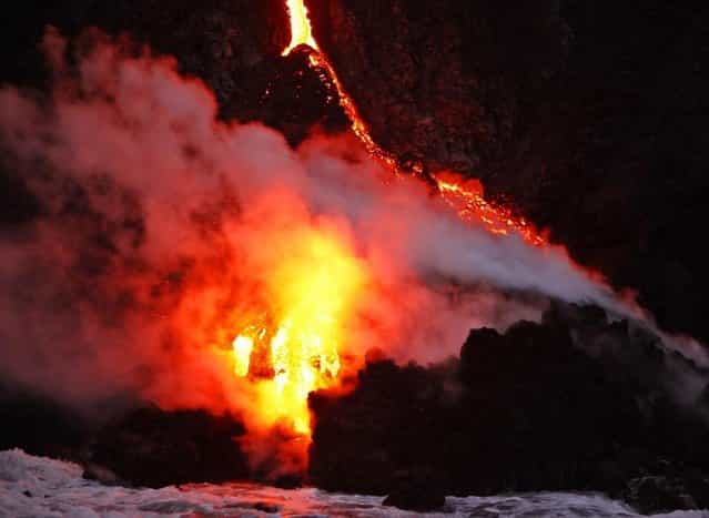 Waves crash over lava as it flows into the ocean near Volcanoes National Park in Kalapana, Hawaii on November 27, 2012