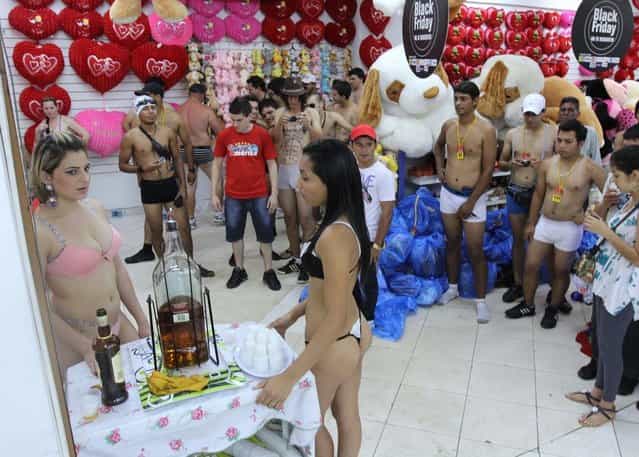 Customers (R) and hostess (L) in underwear take part in a special promotion at a mall in Ciudad del Este, Paraguay, on December 2, 2012. AFP PHOTO/ JOSE ESPINOLA (Photo credit should read JOSE ESPINOLA/AFP/Getty Images)