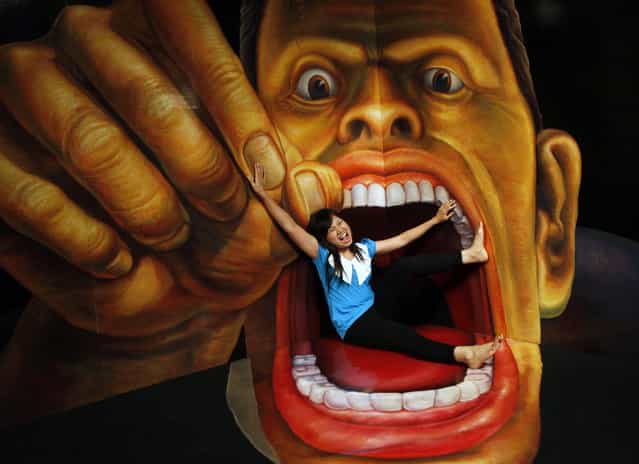 A visitor poses with a 3D art work during a Japanese Trick Art exhibition at a shopping mall in Jakarta, Indonesia, Tuesday, Dec. 4, 2012. (AP Photo/Dita Alangkara)