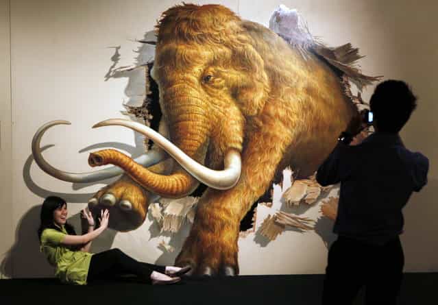 A visitor has her photo taken by a friend as she poses with a 3D art work during a Japanese Trick Art exhibition at a shopping mall in Jakarta, Indonesia, Tuesday, Dec. 4, 2012. (AP Photo/Dita Alangkara)
