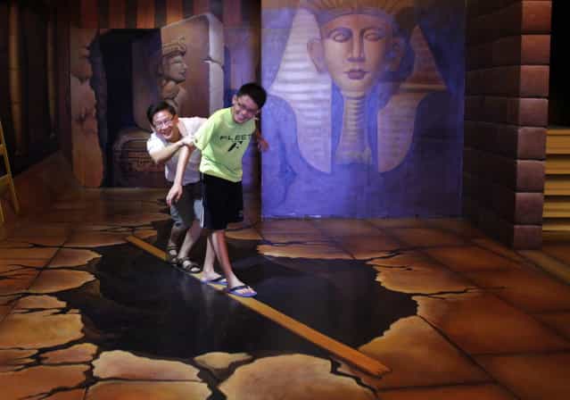 Visitors pose for a photo with a 3D artwork at Trick Art Museum in Shah Alam, outside Kuala Lumpur, Malaysia, Tuesday, Dec. 4, 2012. (AP Photo/Lai Seng Sin)