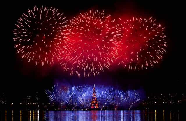 Fireworks explode over the floating Christmas tree in Lagoa Lake at the annual holiday tree lighting event in Rio de Janeiro, Brazil. The Christmas tree, decorated with millions of lights, is believed to be one of the largest in the world. (Photo by Silvia Izquierdo/Associated Press)
