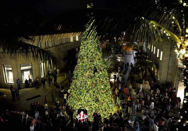 Santa Claus greets visitors as a large Christmas tree towers over Worth Avenue in Palm Beach. (Photo by Chris Salata/The Palm Beach Daily News)