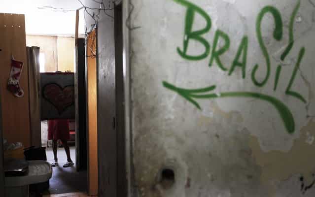 A member of Brazil's Movimento dos Sem-Teto (Roofless Movement) uses a board to gain privacy in one of the 11 empty buildings that the movement took over recently, in the centre of Sao Paulo, December 4, 2012. According to City Hall, there are some 400,000 people in need of stable housing, including the 4,000 families of the Roofless Movement who are squatting in abandoned or vacant buildings that range from apartment blocks to hotels, in Sao Paulo, the largest city in South America. (Photo by Nacho Doce/Reuters)