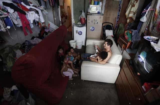 Members of Brazil's Movimento dos Sem-Teto (Roofless Movement) sit on couches in one of the 11 empty buildings that the movement took over recently, in the centre of Sao Paulo, December 4, 2012. According to City Hall, there are some 400,000 people in need of stable housing, including the 4,000 families of the Roofless Movement who are squatting in abandoned or vacant buildings that range from apartment blocks to hotels, in Sao Paulo, the largest city in South America. Picture taken December 4, 2012. (Photo by Nacho Doce/Reuters)
