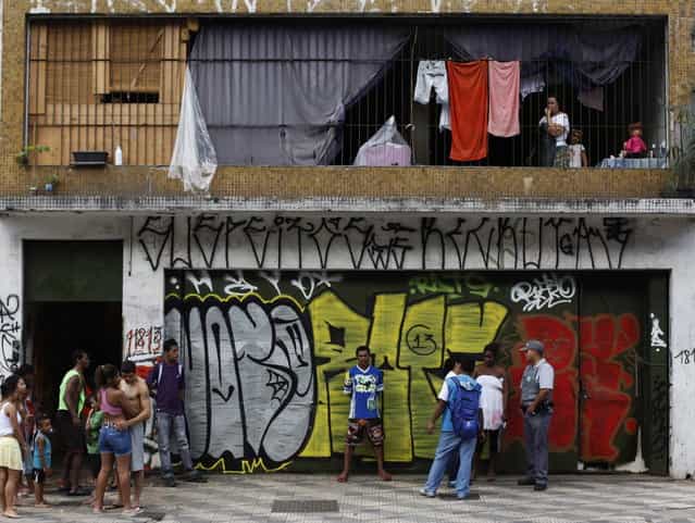 A leader (2nd R, white smock) of Brazil's Movimento dos Sem-Teto (Roofless Movement) speaks to a state health worker (in blue) and a policeman, outside one of the 11 empty buildings that the movement took over recently, in the centre of Sao Paulo, December 4, 2012. According to City Hall, there are some 400,000 people in need of stable housing, including the 4,000 families of the Roofless Movement who are squatting in abandoned or vacant buildings that range from apartment blocks to hotels, in Sao Paulo, the largest city in South America. (Photo by Nacho Doce/Reuters)
