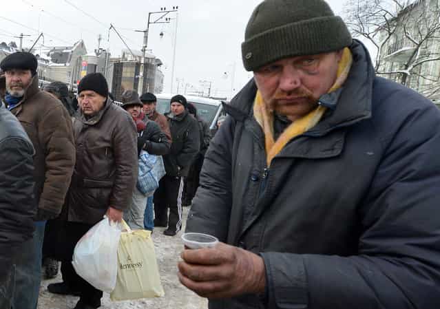 Homeless people queue to get free hot food organized by social services during frost winter day in-Kiev on December 18, 2012. Nineteen people died of exposure in Ukraine in the last 24 hours amid temperatures of minus 20 degrees Celsius (minus 4 degrees Fahrenheit), bringing the toll this month to 37, the health ministry said Tuesday. (Photo by Sergei Supinsky/AFP Photo)