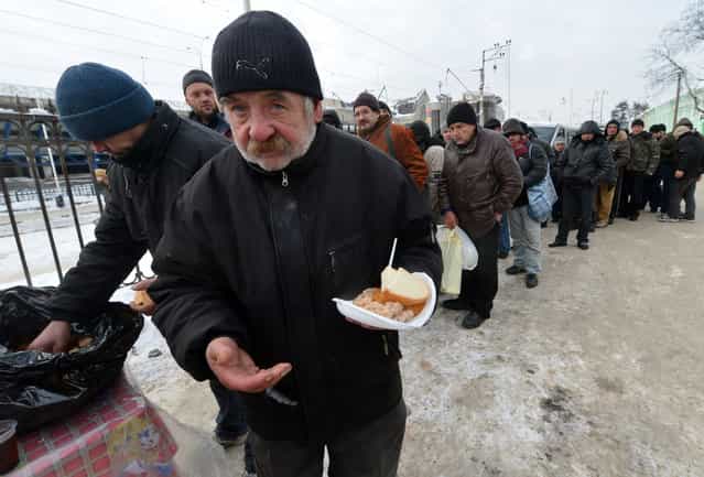 Homeless people queue to get free hot food delivered by social services in Kiev on December 18, 2012. Nineteen people died of exposure in Ukraine in the last 24 hours amid temperatures of minus 20 degrees Celsius (minus 4 degrees Fahrenheit), bringing the toll this month to 37, the health ministry said. (Photo by Sergei Supinsky/AFP Photo)