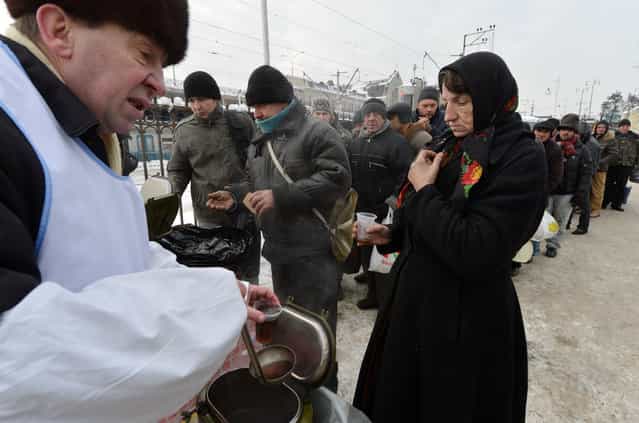 Homeless people queue to get free hot food organized by social services during frost winter day in Kiev on December 18, 2012. Nineteen people died of exposure in Ukraine in the last 24 hours amid temperatures of minus 20 degrees Celsius (minus 4 degrees Fahrenheit), bringing the toll this month to 37, the health ministry said Tuesday. (Photo by Sergei Supinsky/AFP Photo)