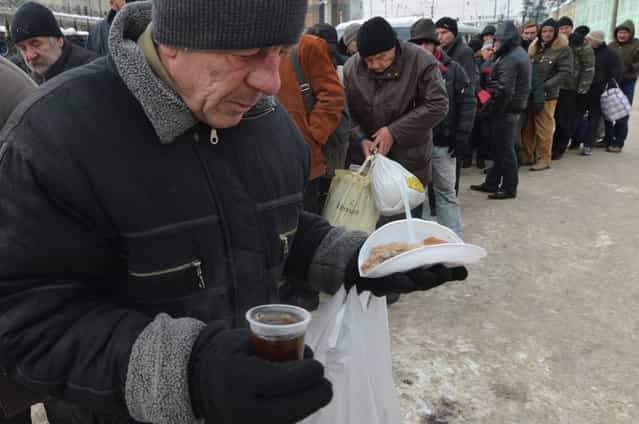Homeless people queue to get free hot food organized by social services duringa frosty winter's day in Kiev on December 18, 2012. Nineteen people died of exposure in Ukraine in the last 24 hours amid temperatures of minus 20 degrees Celsius (minus 4 degrees Fahrenheit), bringing the toll this month to 37, the health ministry said Tuesday. (Photo by Sergei Supinsky/AFP Photo)