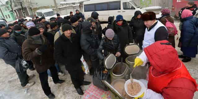 Homeless people queue to get free hot food organized by social services during a frosty winter's day in Kiev on December 18, 2012. Nineteen people died of exposure in Ukraine in the last 24 hours amid temperatures of minus 20 degrees Celsius (minus 4 degrees Fahrenheit), bringing the toll this month to 37, the health ministry said Tuesday. (Photo by Sergei Supinsky/AFP Photo)