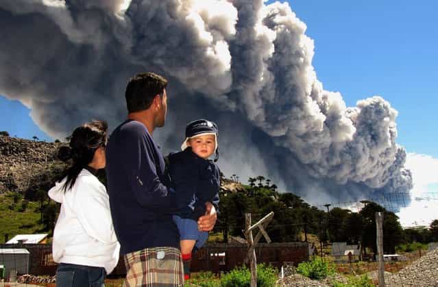 A family watches the Copahue volcano spewing ashes from Caviahue, Neuquen province, Argentina, some 1500 km southwest of Buenos Aires on December 22, 2012. The authorities of Chile and Argentina issued yellow alerts due to the eruption of the Copahue volcano, placed in the border between both countries. (Photo by Antonio Huglich/AFP Photo)