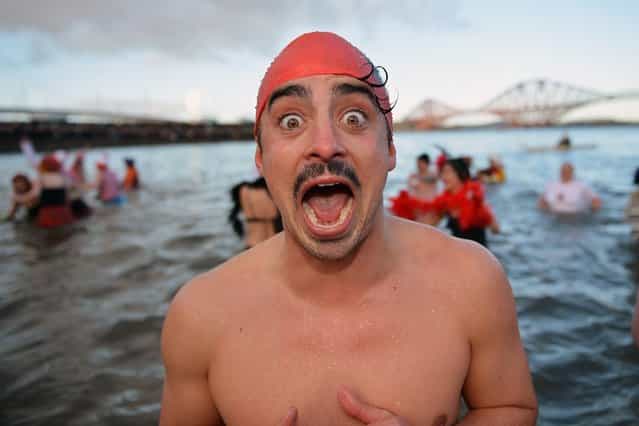A man reacts as he joined by over 1,000 New Year swimmers, many in costume, braved freezing conditions in the River Forth in front of the Forth Rail Bridge during the annual Loony Dook Swim on January 1, 2013 in South Queensferry, Scotland. Thousands of people gathered last night to see in the New Year at Hogmanay celebrations in towns and cities across Scotland. (Photo by Jeff J. Mitchell)