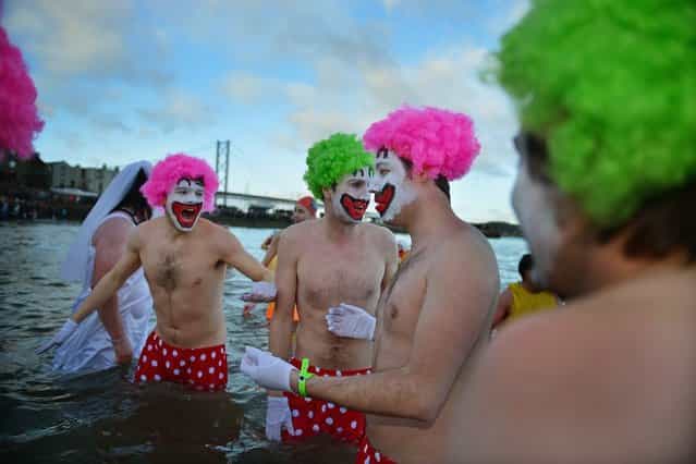 Men dressed as clowns joined over 1,000 New Year swimmers, many in costume, braved freezing conditions in the River Forth in front of the Forth Rail Bridge during the annual Loony Dook Swim on January 1, 2013 in South Queensferry, Scotland. Thousands of people gathered last night to see in the New Year at Hogmanay celebrations in towns and cities across Scotland. (Photo by Jeff J. Mitchell)