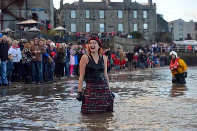 SOUTH QUEENSFERRY, SCOTLAND - JANUARY 01: A woman makes her way in the water wearing a kilt as she joined around 1,000 New Year swimmers, many in costume, braved freezing conditions in the River Forth in front of the Forth Rail Bridge during the annual Loony Dook Swim on January 1, 2013 in South Queensferry, Scotland. Thousands of people gathered last night to see in the New Year at Hogmanay celebrations in towns and cities across Scotland.. (Photo by Jeff J. Mitchell)