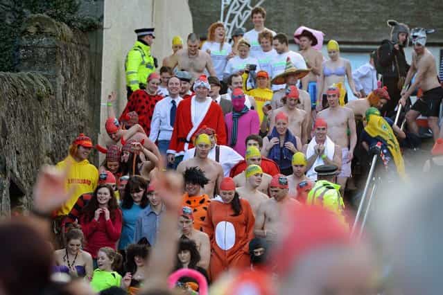 SOUTH QUEENSFERRY, SCOTLAND - JANUARY 01: Revelers make their way down steps as they joined around 1,000 New Year swimmers, many in costume, braved freezing conditions in the River Forth in front of the Forth Rail Bridge during the annual Loony Dook Swim on January 1, 2013 in South Queensferry, Scotland. Thousands of people gathered last night to see in the New Year at Hogmanay celebrations in towns and cities across Scotland.. (Photo by Jeff J. Mitchell)