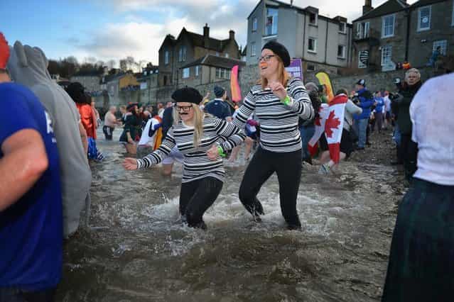 Over 1,000 New Year swimmers, many in costume, brave the freezing conditions in the River Forth in front of the Forth Rail Bridge during the annual Loony Dook Swim on January 1, 2013 in South Queensferry, Scotland. Thousands of people gathered last night to see in the New Year at Hogmanay celebrations in towns and cities across Scotland. (Photo by Jeff J. Mitchell)