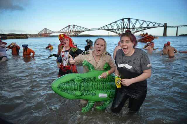 Over 1,000 New Year swimmers, many in costume, brave the freezing conditions in the River Forth in front of the Forth Rail Bridge during the annual Loony Dook Swim on January 1, 2013 in South Queensferry, Scotland. Thousands of people gathered last night to see in the New Year at Hogmanay celebrations in towns and cities across Scotland. (Photo by Jeff J. Mitchell)